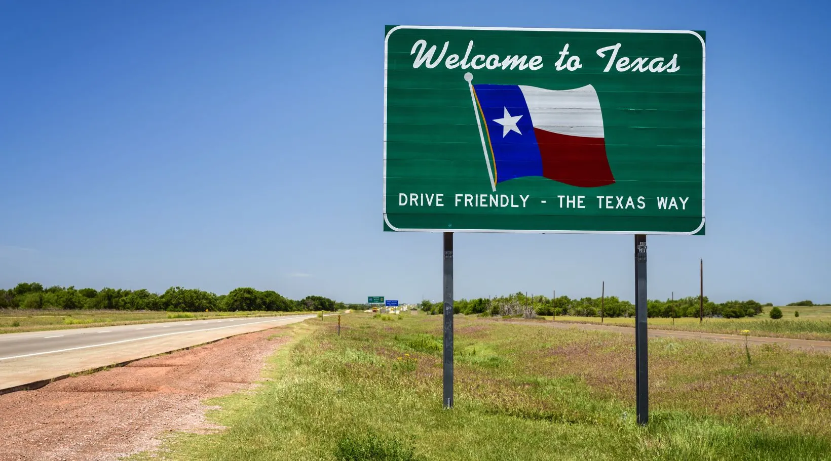 Welcome to Texas road sign featuring the state flag and slogan “Drive Friendly – The Texas Way.