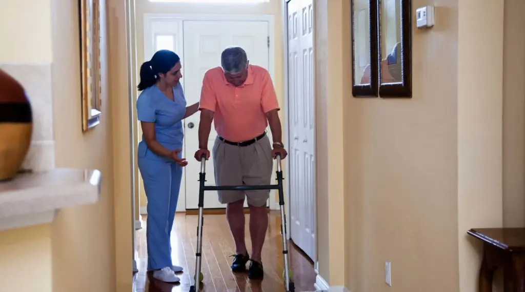 Care worker assisting elderly man with a walker during home health care visit for recovery.