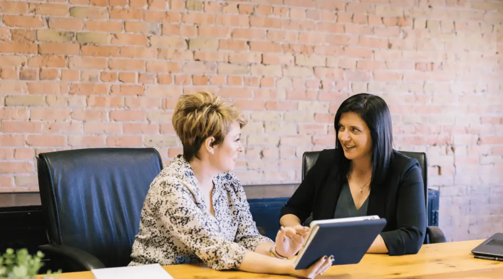 Coworkers in a meeting planning workflow and reviewing data on a tablet using ShiftCare.