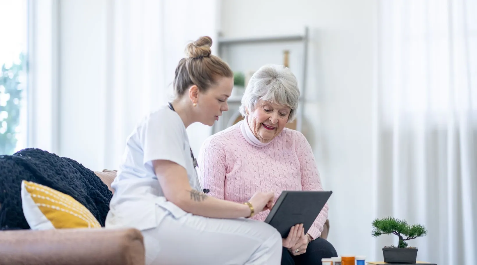Caregiver and senior reviewing care information on tablet during home visit managed with ShiftCare.