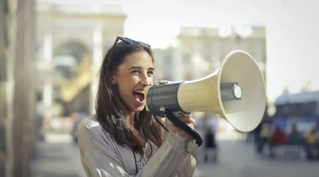 Young woman using megaphone to spread awareness for home health agencies, ShiftCare.