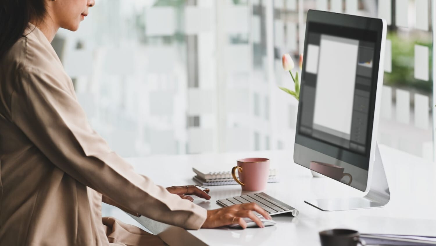 Woman managing client records using care management software on desktop in a bright, modern office space.