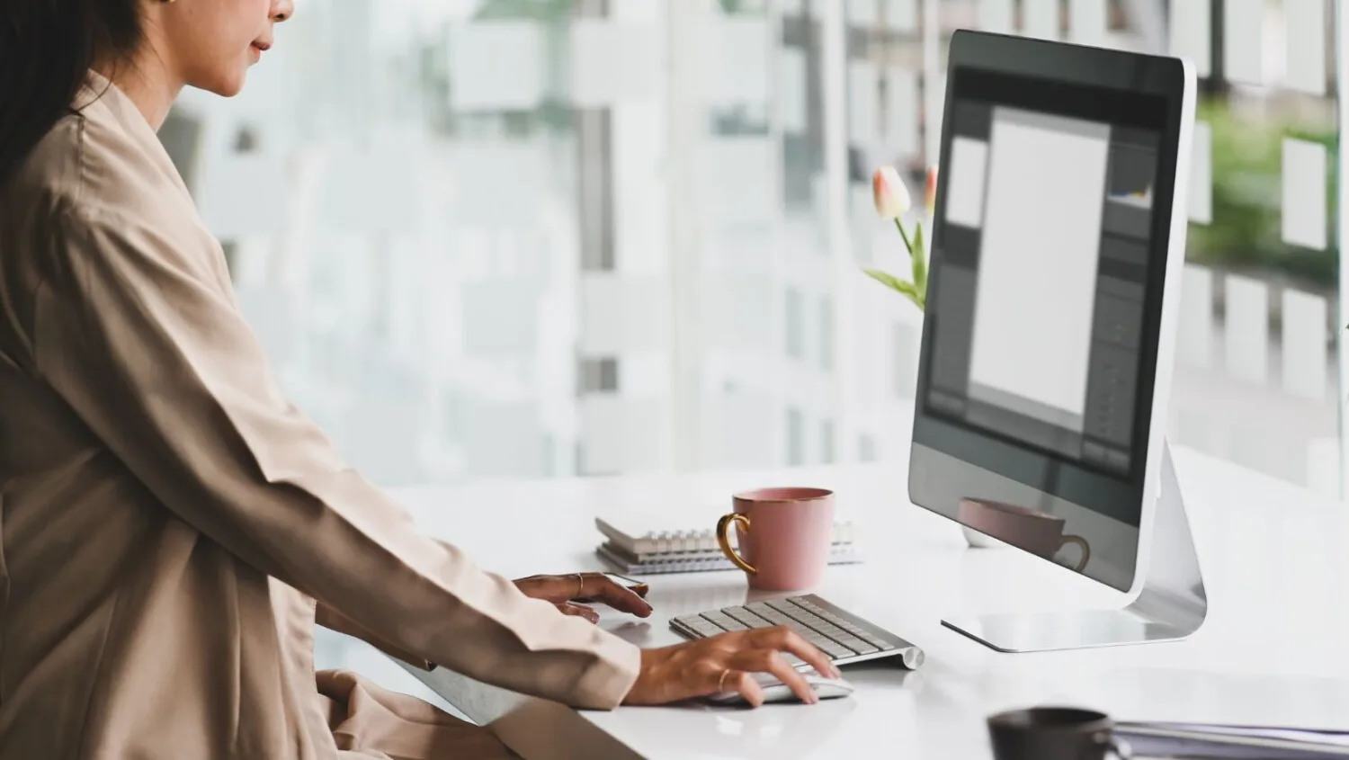 Woman managing client records using care management software on desktop in a bright, modern office space.