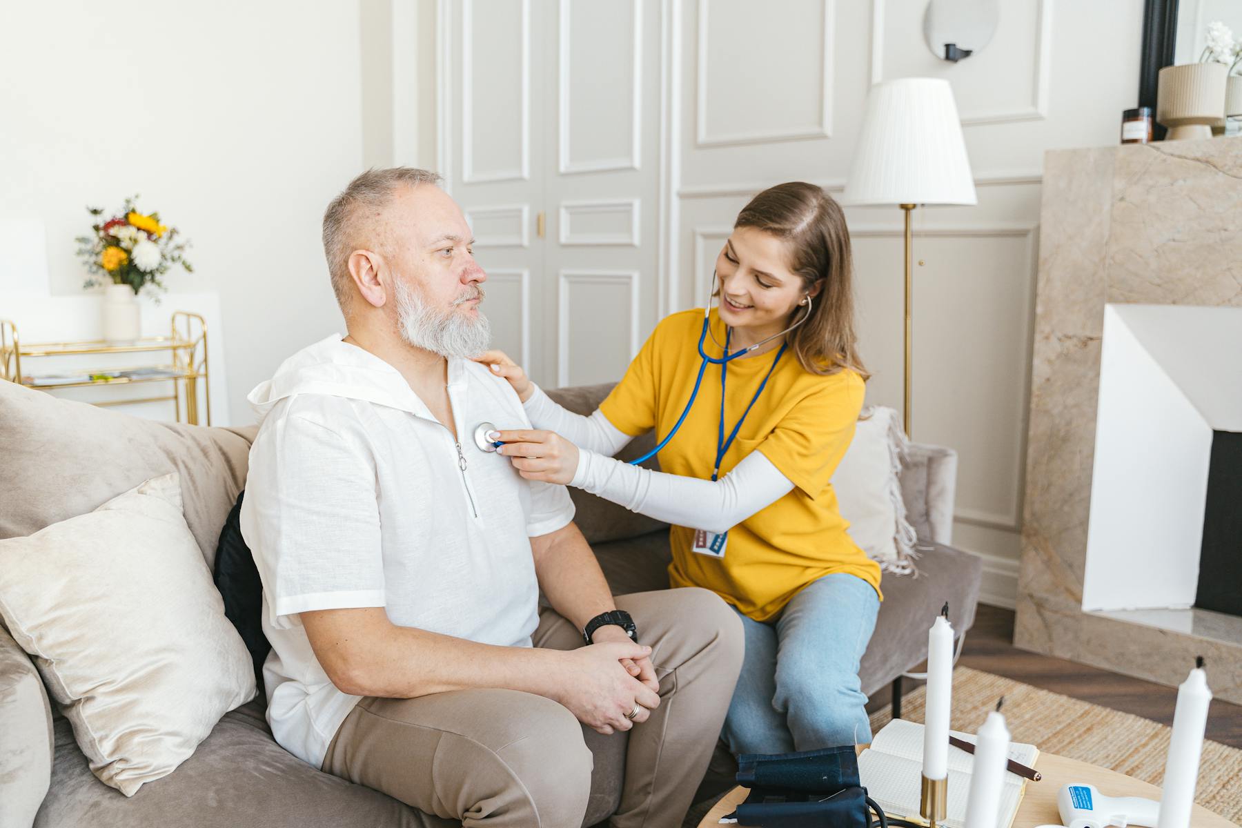 Care service provider in yellow shirt attending to older patient
