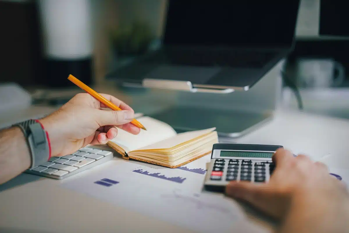 A person doing invoices with calculator and paper