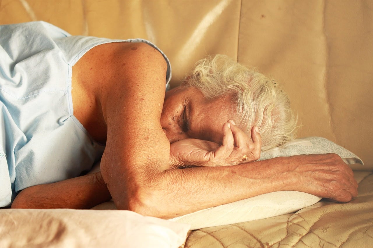 Older woman sleeping on her side on a bed