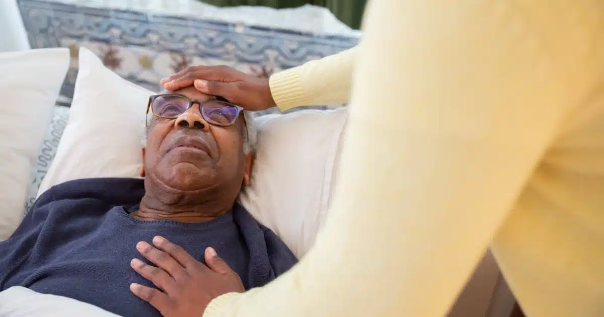 An older man in a blue sweater lying down on the bed