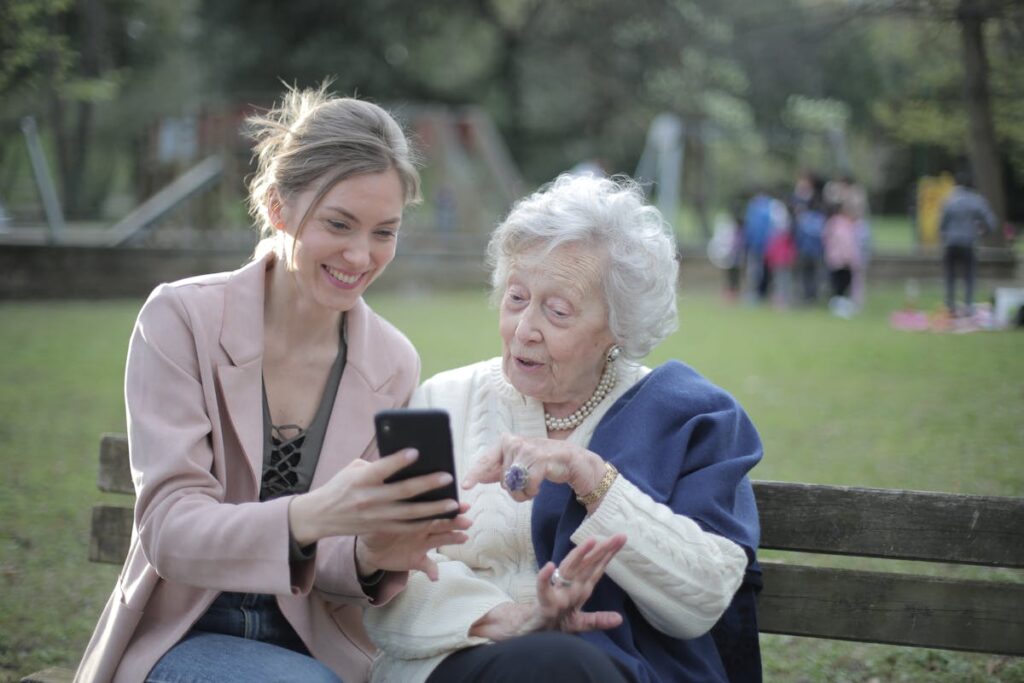 A cheerful caregiver helping an elderly client use the phone