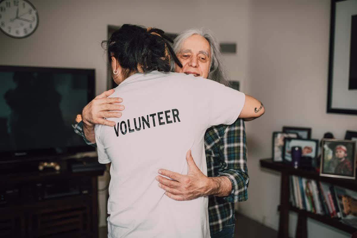 A volunteer and an older patient hugging
