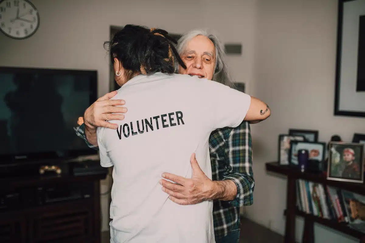 A volunteer and an older patient hugging