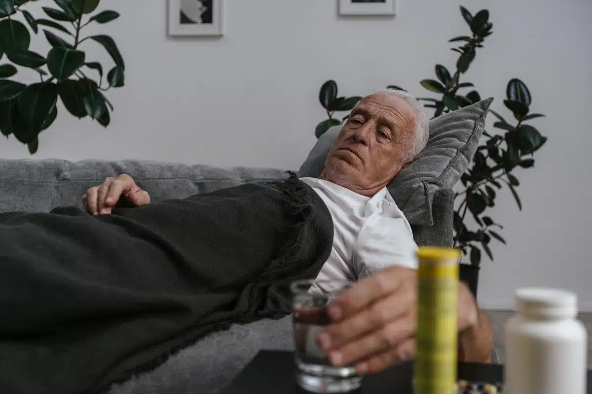 And older adult in bed reaching for their medicine
