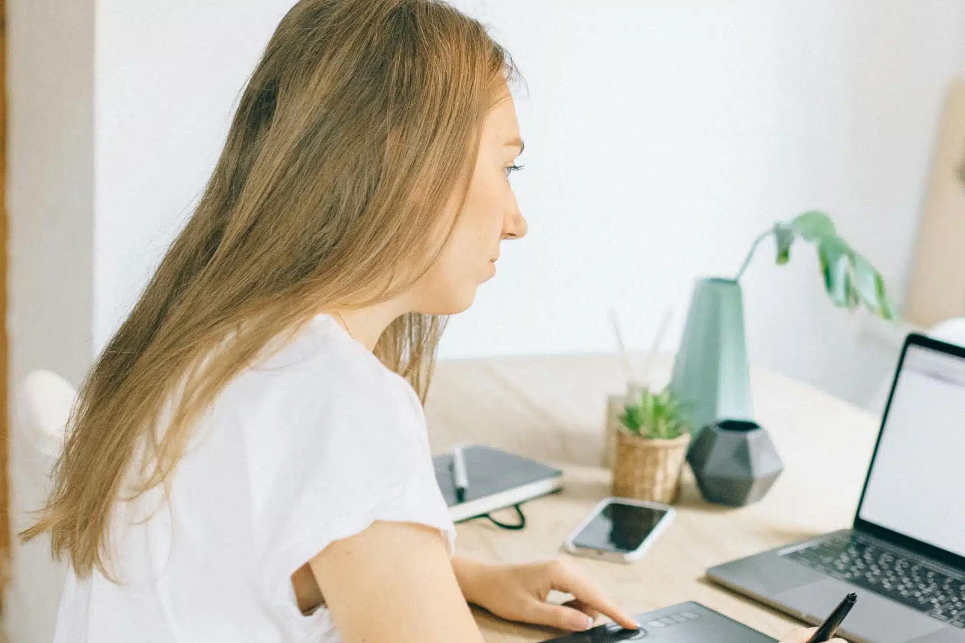 Woman in white working and looking at her laptop