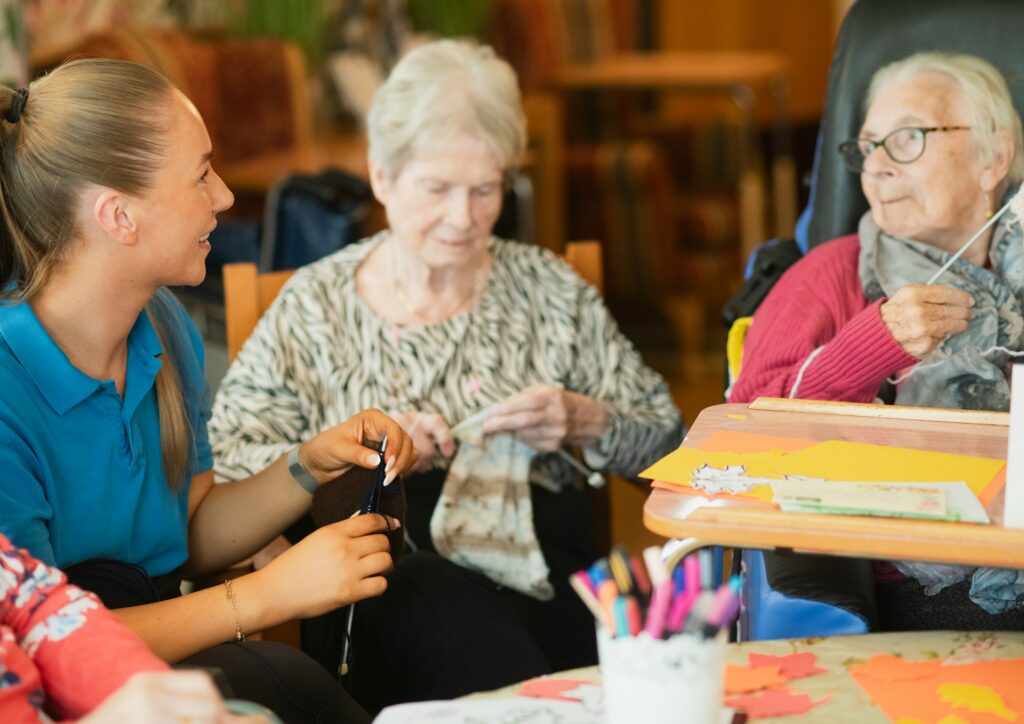 A caregiver assisting two senior patients