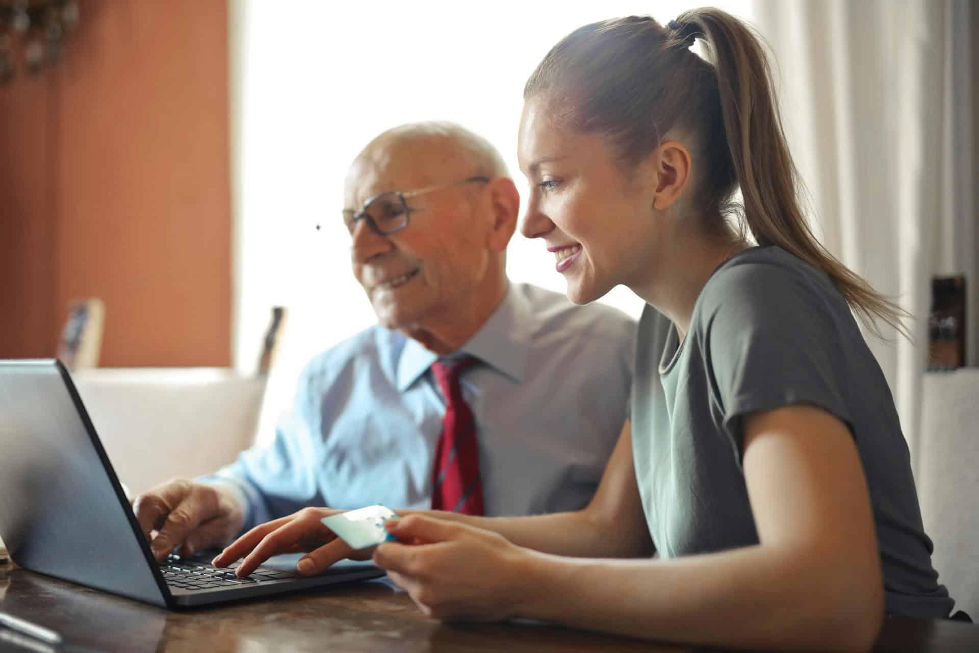 Caregiver teaching older male to use a laptop