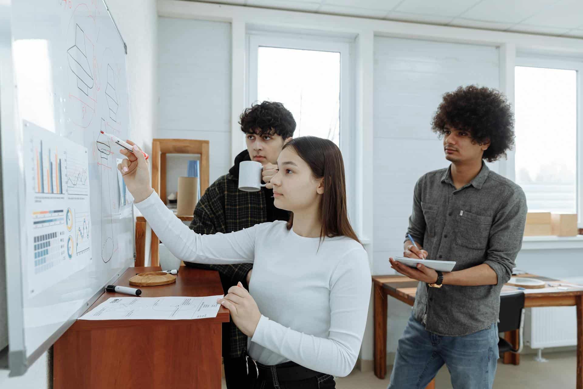 A female worker writing on a board with two of her coworkers