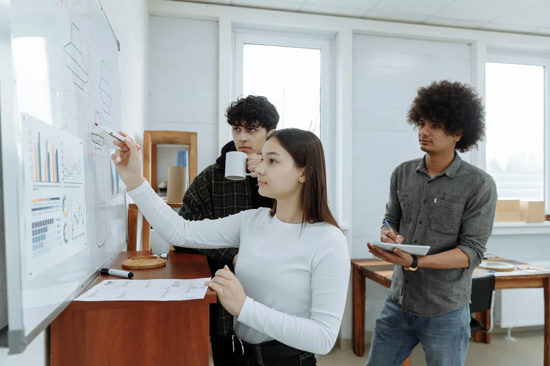 A female worker writing on a board with two of her coworkers