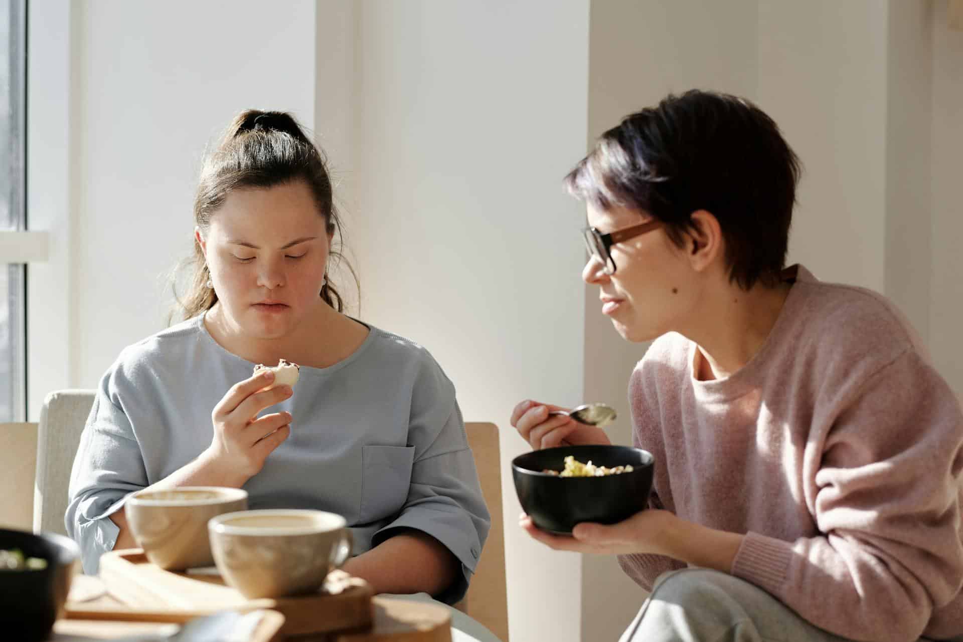 A female carer assisting person with disability with food