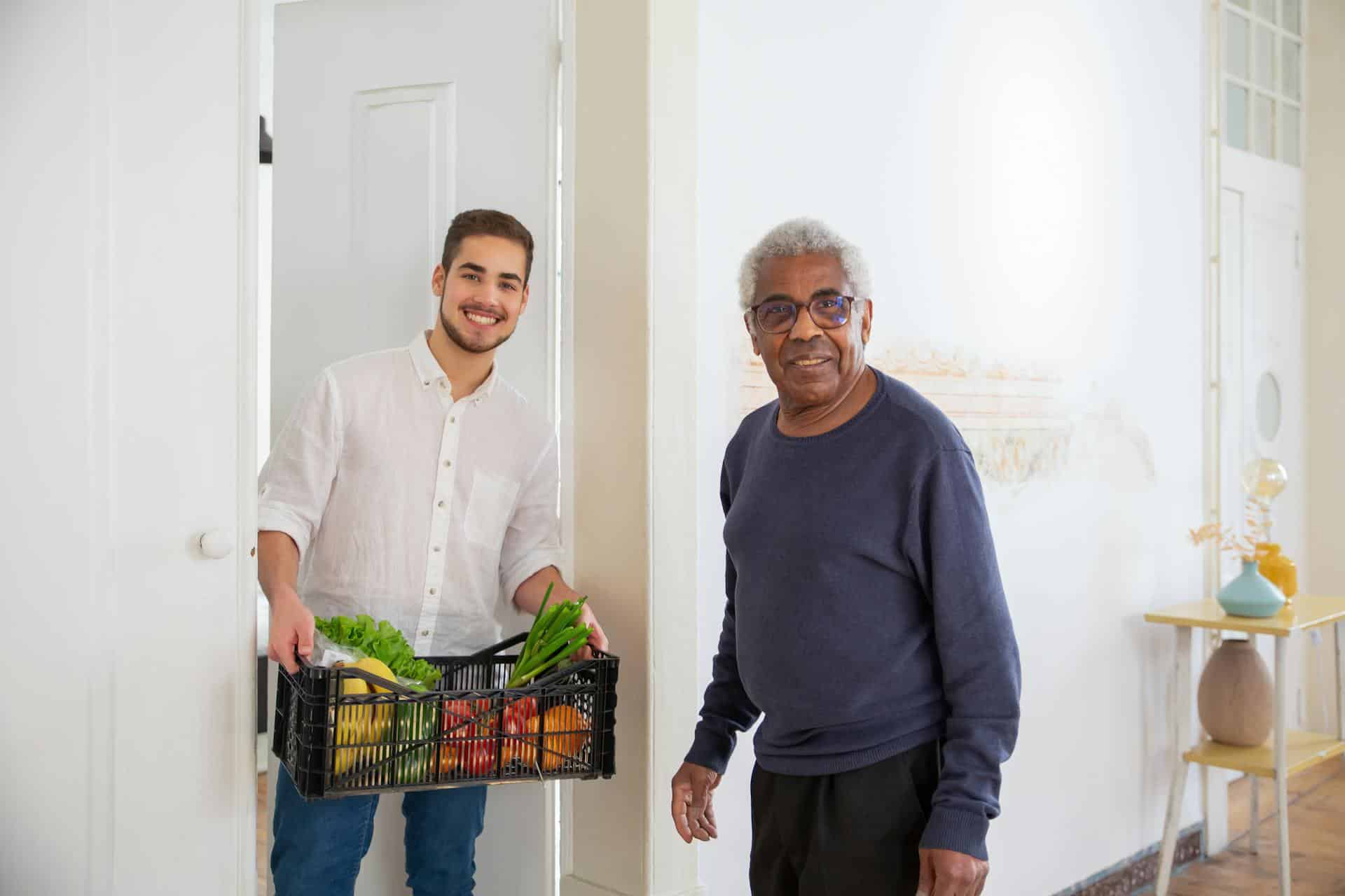 A carer in a white shirt helping older adult with cooking