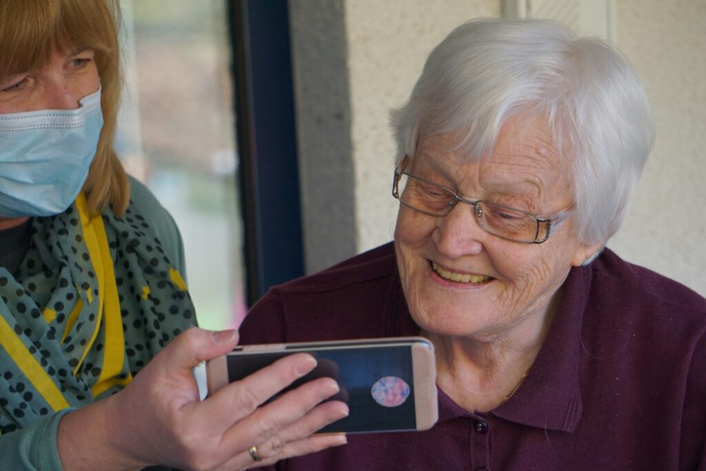 Carer showing an elderly client her smartphone