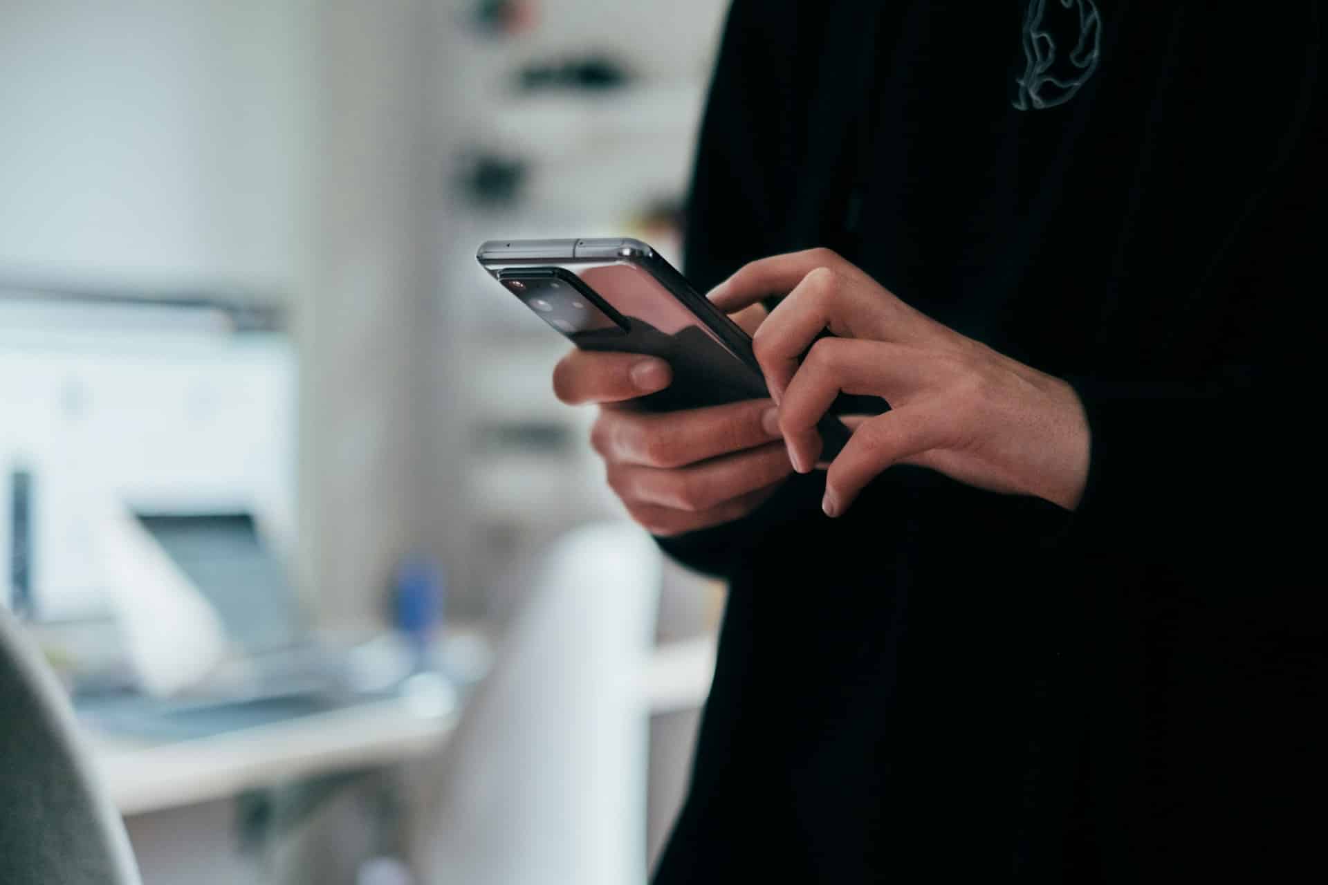 Person's hands holding a black cellphone
