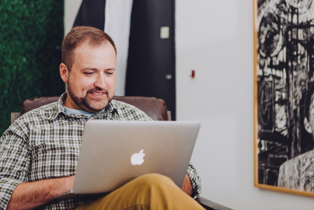 Carer smiling while working on his laptop