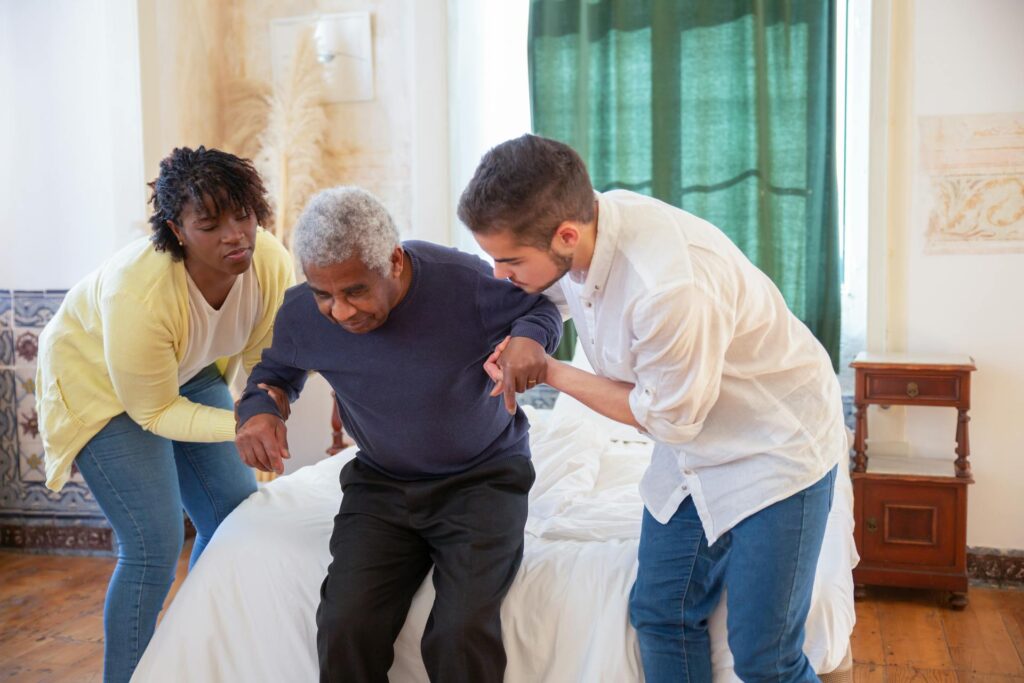 Two carers assisting an elderly man who is standing up