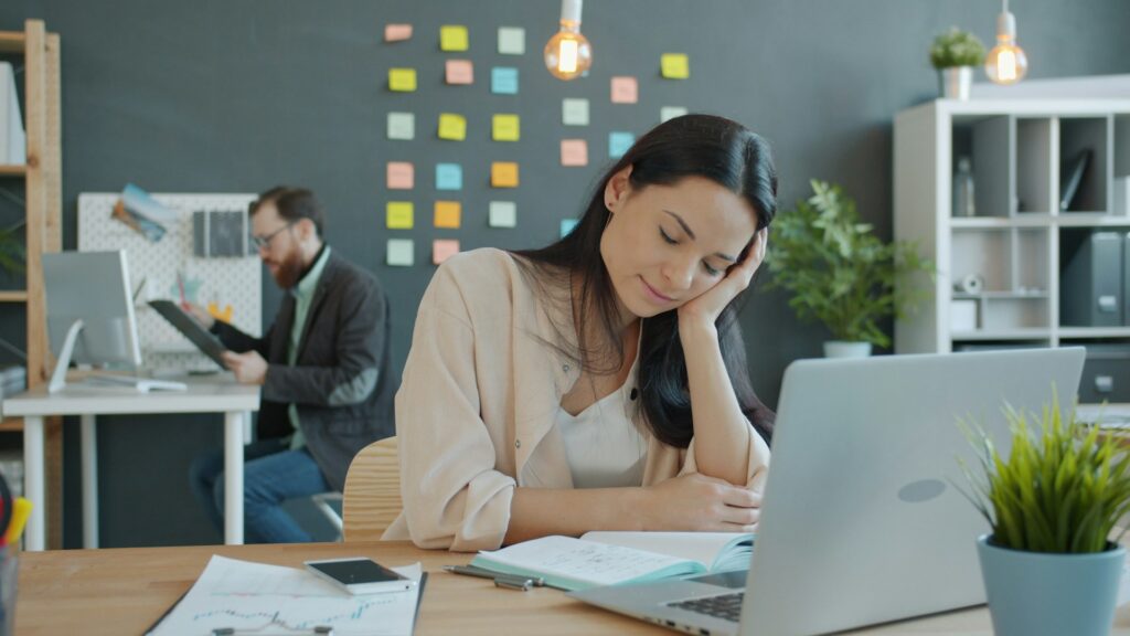 Woman resting on her hand while working on a laptop