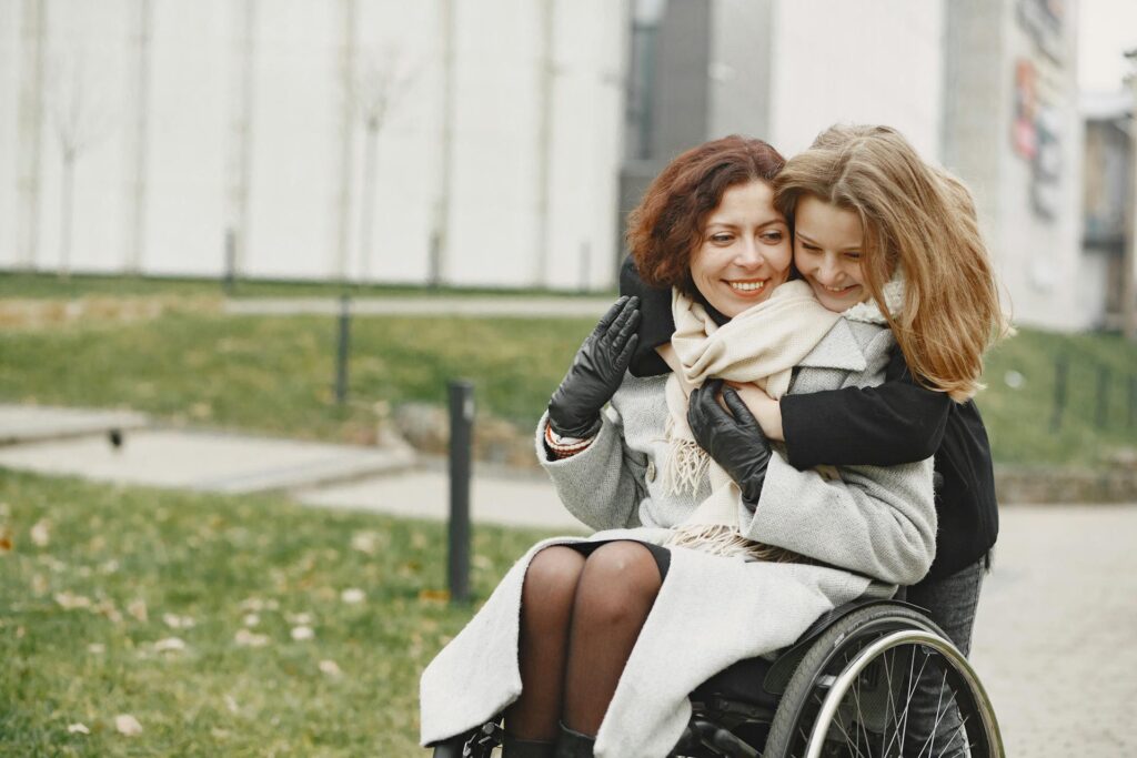 A person without disability hugging a wheelchair user