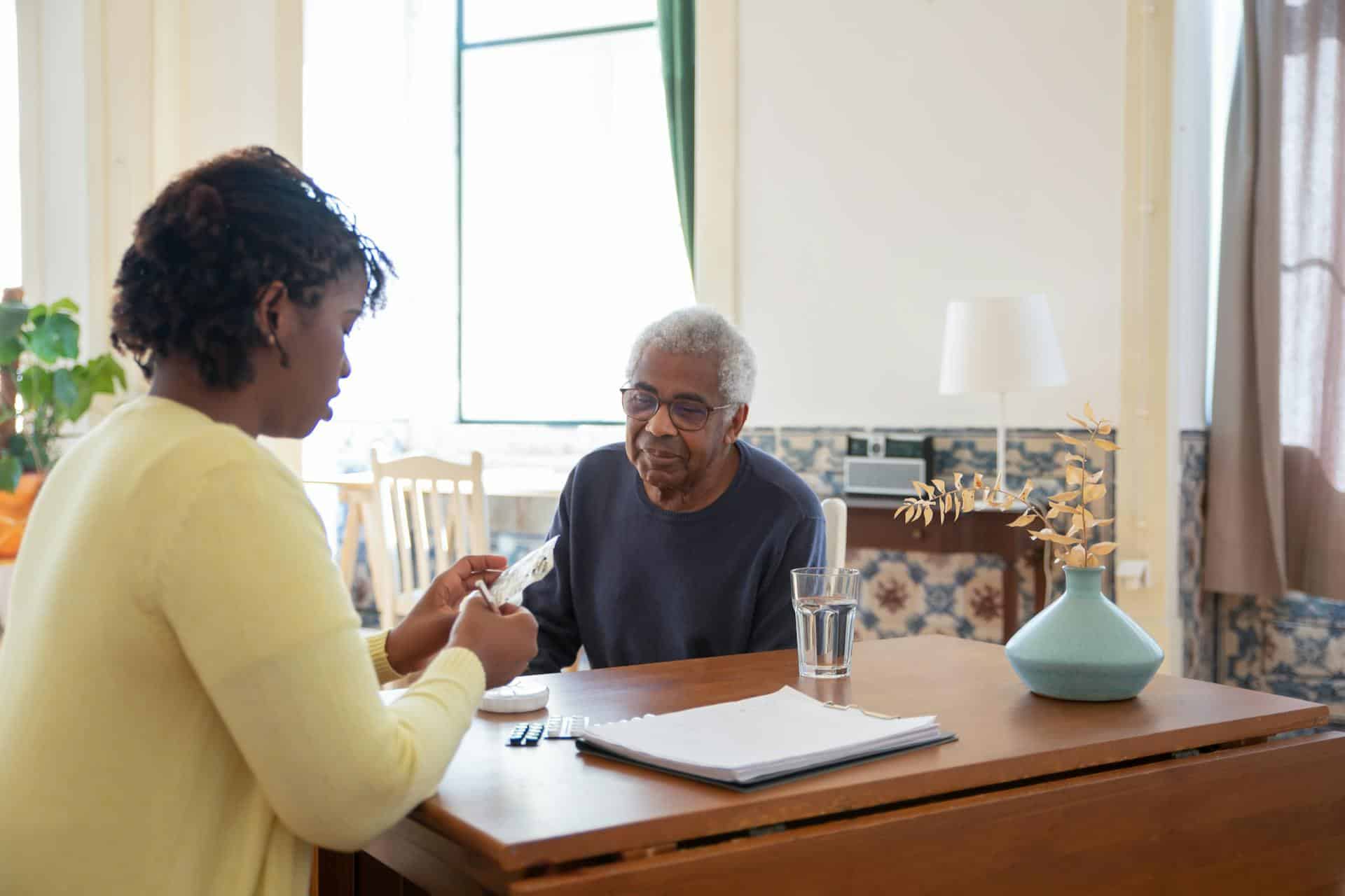 Caregiver assisting older patient and writing notes