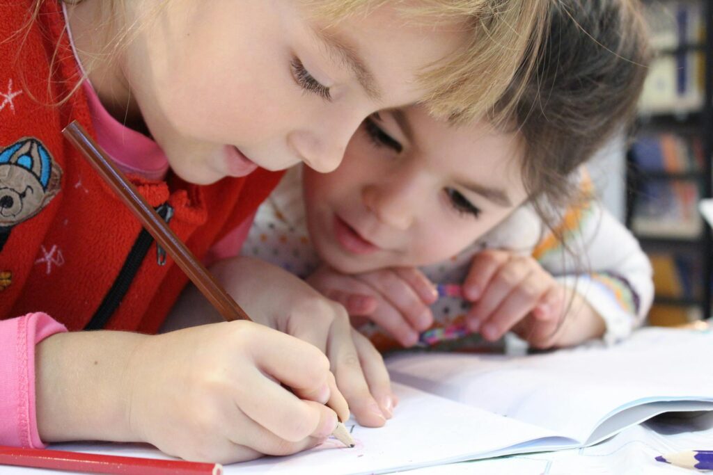 Two children writing on a notebook